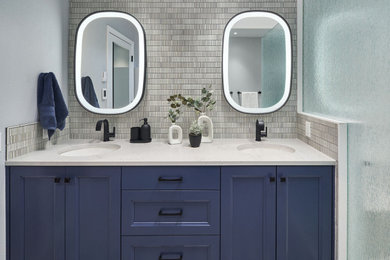 Источник вдохновения для домашнего уюта: главная ванная комната среднего размера в стиле неоклассика (современная классика) с фасадами с утопленной филенкой, синими фасадами, угловым душем, унитазом-моноблоком, серой плиткой, керамической плиткой, белыми стенами, полом из керамической плитки, врезной раковиной, столешницей из искусственного кварца, синим полом, душем с распашными дверями, серой столешницей, сиденьем для душа, тумбой под две раковины, встроенной тумбой и многоуровневым потолком
