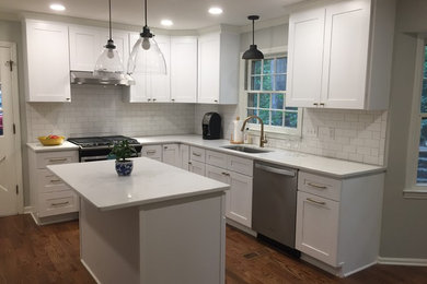 Design ideas for a mid-sized traditional u-shaped kitchen in Atlanta with shaker cabinets, white cabinets, quartz benchtops, white splashback, stainless steel appliances, dark hardwood floors, with island, brown floor, white benchtop, an undermount sink and subway tile splashback.
