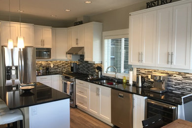 Mid-sized trendy l-shaped medium tone wood floor eat-in kitchen photo in Vancouver with a double-bowl sink, recessed-panel cabinets, white cabinets, granite countertops, gray backsplash, glass tile backsplash, stainless steel appliances and an island