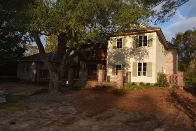 Large traditional beige two-story brick exterior home idea in New Orleans with a hip roof