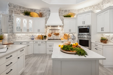 Huge tuscan u-shaped porcelain tile, gray floor and coffered ceiling open concept kitchen photo in Tampa with a drop-in sink, louvered cabinets, white cabinets, marble countertops, white backsplash, brick backsplash, stainless steel appliances, an island and multicolored countertops