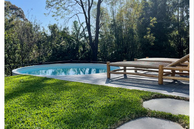 Design ideas for a mid-sized modern backyard round pool in Sunshine Coast with decking.