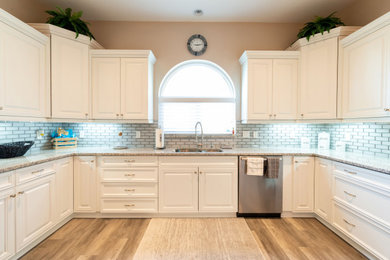 Example of a mid-sized transitional u-shaped vinyl floor and brown floor eat-in kitchen design in Other with a double-bowl sink, shaker cabinets, white cabinets, granite countertops, white backsplash, subway tile backsplash, stainless steel appliances, no island and multicolored countertops