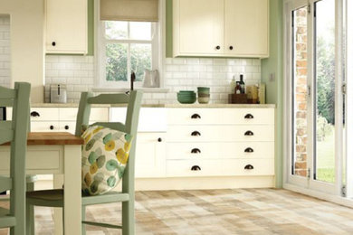 Mid-sized country single-wall light wood floor and brown floor eat-in kitchen photo in Toronto with a farmhouse sink, flat-panel cabinets, white cabinets, granite countertops, white backsplash and subway tile backsplash
