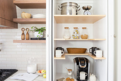 Eat-in kitchen - mid-century modern medium tone wood floor eat-in kitchen idea in Cleveland with shaker cabinets, white cabinets, quartzite countertops, white backsplash, ceramic backsplash, stainless steel appliances, an island and white countertops