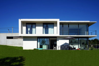 Imagen de fachada de casa blanca y blanca moderna de tamaño medio de dos plantas con revestimientos combinados, tejado plano y tejado de varios materiales