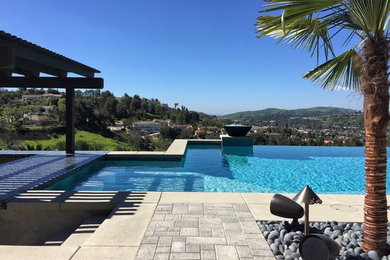 Example of a large trendy backyard concrete paver and rectangular infinity hot tub design in Los Angeles