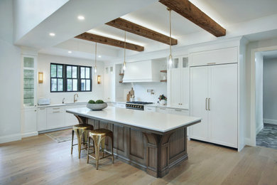 Design ideas for a mid-sized country l-shaped open plan kitchen in Toronto with an undermount sink, quartzite benchtops, white splashback, panelled appliances, light hardwood floors, with island, white benchtop and exposed beam.