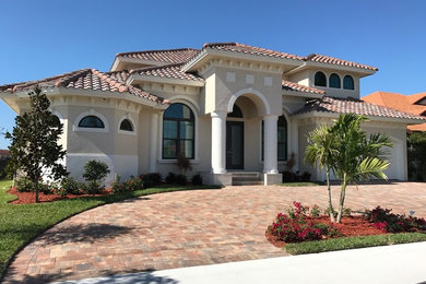 Mid-sized mediterranean beige two-story stucco exterior home idea in Miami with a hip roof