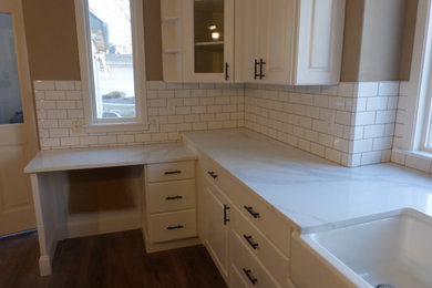 Example of a large kitchen design in Boise with raised-panel cabinets, white cabinets, quartz countertops, white backsplash, ceramic backsplash, an island and white countertops