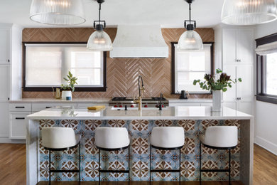 Example of a mid-sized tuscan l-shaped medium tone wood floor and brown floor eat-in kitchen design in San Diego with a farmhouse sink, shaker cabinets, white cabinets, quartzite countertops, pink backsplash, porcelain backsplash, stainless steel appliances, an island and white countertops