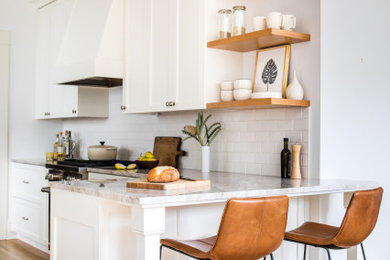 Inspiration for a mid-sized galley eat-in kitchen in Portland with a farmhouse sink, recessed-panel cabinets, white cabinets, white splashback, subway tile splashback, panelled appliances, medium hardwood floors, no island, brown floor and grey benchtop.