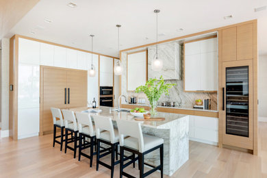 Photo of a contemporary kitchen in Other with flat-panel cabinets, marble benchtops, white splashback, marble splashback, panelled appliances, light hardwood floors, with island, beige floor, white benchtop, a double-bowl sink and white cabinets.