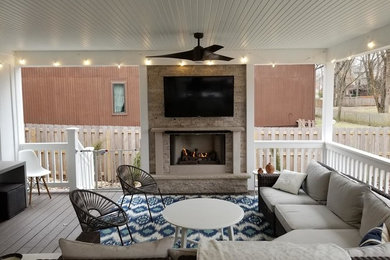 Photo of a mid-sized contemporary backyard verandah in Kansas City with with fireplace, decking and a roof extension.