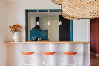 Exemple d'un grand bar de salon moderne avec des tabourets, un plan de travail en bois, une crédence bleue, une crédence en céramique, parquet clair et un plan de travail orange.