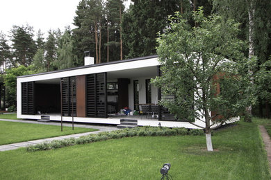 Photo of a mid-sized contemporary one-storey white house exterior in Moscow with metal siding, a flat roof and a metal roof.