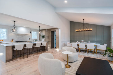 Inspiration for a large transitional l-shaped open plan kitchen in DC Metro with a single-bowl sink, shaker cabinets, white cabinets, quartz benchtops, white splashback, porcelain splashback, stainless steel appliances, light hardwood floors, with island, beige floor and white benchtop.