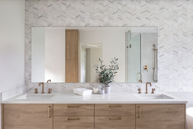 Example of a mid-sized transitional master white tile and marble tile porcelain tile, gray floor and double-sink bathroom design in Seattle with flat-panel cabinets, light wood cabinets, a two-piece toilet, white walls, an undermount sink, quartz countertops, a hinged shower door, white countertops and a floating vanity