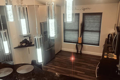 Example of a mid-sized minimalist porcelain tile kitchen design in Baltimore with a single-bowl sink, flat-panel cabinets, beige cabinets, granite countertops, beige backsplash, glass tile backsplash and stainless steel appliances