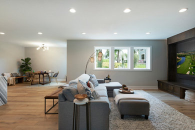 Example of a large minimalist look-out light wood floor, beige floor, wallpaper ceiling and wallpaper basement design in Minneapolis with a bar, gray walls, a corner fireplace and a tile fireplace