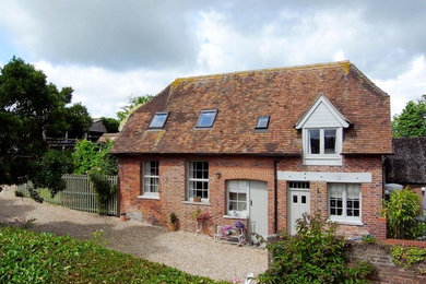 This is an example of a country two-storey brick exterior in Dorset with a clipped gable roof.