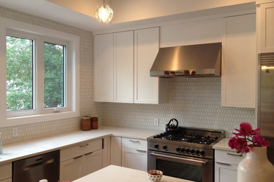 Large trendy u-shaped light wood floor and brown floor eat-in kitchen photo in Edmonton with an undermount sink, shaker cabinets, white cabinets, quartz countertops, white backsplash, porcelain backsplash, stainless steel appliances and an island