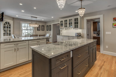 Inspiration for a large transitional galley light wood floor and beige floor open concept kitchen remodel in Boston with an undermount sink, shaker cabinets, white cabinets, granite countertops, white backsplash, porcelain backsplash, paneled appliances and two islands