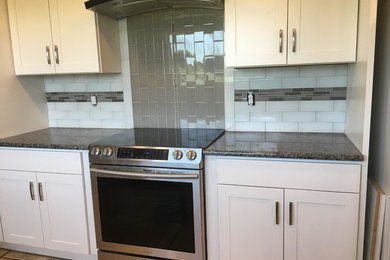 Mid-sized transitional single-wall kitchen photo in Other with shaker cabinets, white cabinets, granite countertops, multicolored backsplash, subway tile backsplash, stainless steel appliances and brown countertops