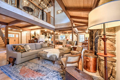 Large open concept light wood floor and exposed beam living room photo in Other with a two-sided fireplace and a stone fireplace