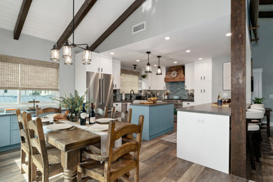 Example of a mid-sized beach style u-shaped vinyl floor, brown floor and wood ceiling eat-in kitchen design in Los Angeles with a farmhouse sink, shaker cabinets, blue cabinets, quartz countertops, blue backsplash, ceramic backsplash, stainless steel appliances, an island and gray countertops