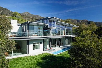 Huge modern white two-story glass exterior home idea in Santa Barbara with a metal roof