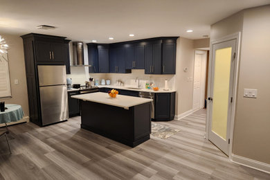 Inspiration for a mid-sized contemporary l-shaped laminate floor and gray floor eat-in kitchen remodel in Newark with an undermount sink, shaker cabinets, blue cabinets, quartz countertops, white backsplash, subway tile backsplash, stainless steel appliances, an island and white countertops