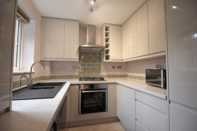 This is an example of a small contemporary u-shaped enclosed kitchen in Other with a double-bowl sink, flat-panel cabinets, grey cabinets, laminate countertops, green splashback, ceramic splashback, stainless steel appliances, concrete flooring and no island.