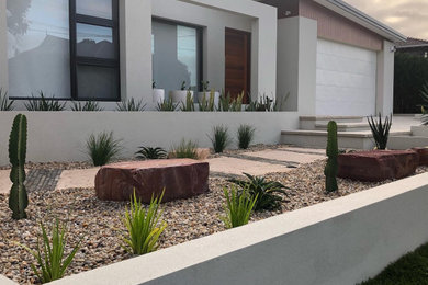Design ideas for a mid-sized contemporary front yard full sun xeriscape in Perth with with raised garden bed and gravel.