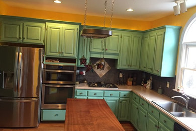 Eat-in kitchen - mid-sized eclectic l-shaped medium tone wood floor eat-in kitchen idea in Charlotte with raised-panel cabinets, green cabinets, wood countertops, gray backsplash, mosaic tile backsplash, an island, a double-bowl sink and stainless steel appliances