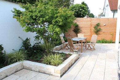 Kleine Klassische Gartenmauer mit direkter Sonneneinstrahlung und Natursteinplatten in München