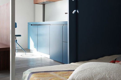Diseño de dormitorio moderno pequeño sin chimenea con paredes azules, suelo laminado y suelo beige