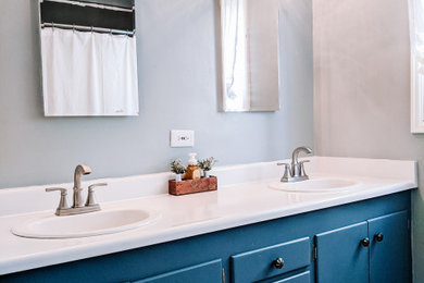 Modelo de cuarto de baño doble y a medida minimalista pequeño con armarios con paneles lisos, puertas de armario azules, bañera esquinera, ducha esquinera, sanitario de dos piezas, paredes azules, lavabo encastrado, encimera de laminado, ducha con cortina, encimeras blancas y papel pintado