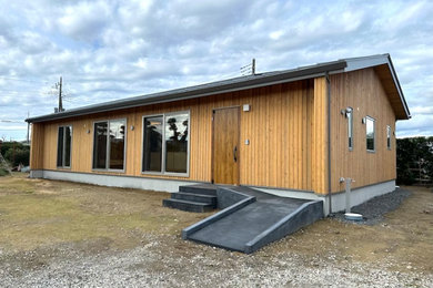 Modelo de fachada de casa marrón y gris de tamaño medio de una planta con revestimiento de madera, tejado a dos aguas, tejado de metal y panel y listón
