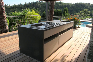 Réalisation d'une grande terrasse arrière méditerranéenne avec une cuisine d'été et une pergola.