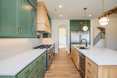 Inspiration for a large galley light wood floor and brown floor eat-in kitchen remodel in Other with an undermount sink, shaker cabinets, quartz countertops, white backsplash, porcelain backsplash, stainless steel appliances, an island and white countertops