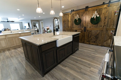 Example of a large country u-shaped gray floor and vinyl floor eat-in kitchen design in Other with a farmhouse sink, raised-panel cabinets, distressed cabinets, granite countertops, white backsplash, porcelain backsplash, stainless steel appliances, an island and multicolored countertops