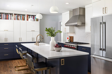 Example of a mid-sized transitional dark wood floor and brown floor eat-in kitchen design in Detroit with blue cabinets, white backsplash, stainless steel appliances, an island and white countertops