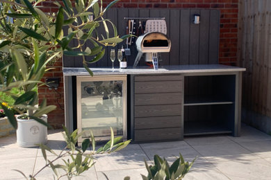 Design ideas for a medium sized contemporary back patio in Hertfordshire with an outdoor kitchen, tiled flooring and no cover.