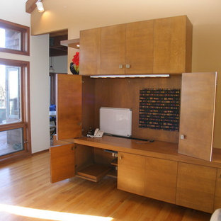 This is an example of a medium sized modern home office and library in San Francisco with yellow walls, light hardwood flooring and a built-in desk.