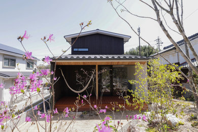 Cette photo montre une façade de maison noire en bois et planches et couvre-joints de taille moyenne et à un étage avec un toit à deux pans, un toit en métal et un toit noir.