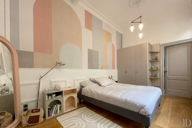 Cette image montre une chambre parentale haussmannienne traditionnelle de taille moyenne avec un sol en bois brun, aucune cheminée, un sol marron et du papier peint.
