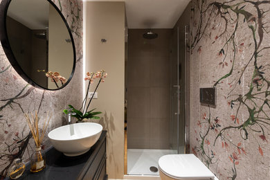 Immagine di una stanza da bagno chic con ante con bugna sagomata, ante nere, parquet chiaro, top in vetro e top nero