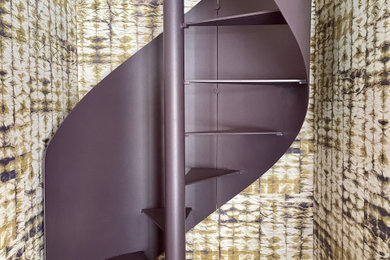 Réalisation d'un escalier hélicoïdal avec des marches en métal, un garde-corps en métal et du papier peint.