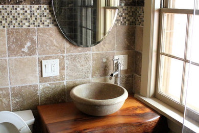 This is an example of a mid-sized contemporary master bathroom in Nashville with a vessel sink, wood benchtops, a one-piece toilet, stone tile and beige walls.